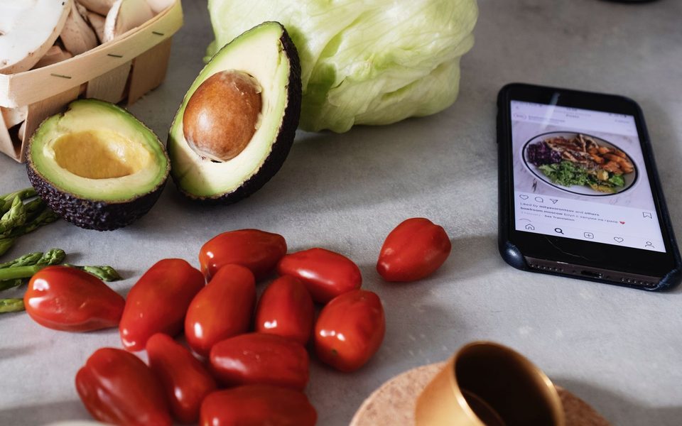 Fresh vegetables and a phone showing a meal photo